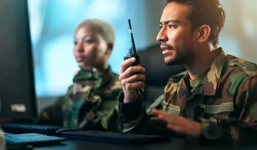 Mann in Militärkleidung hält Funkgerät in Hand