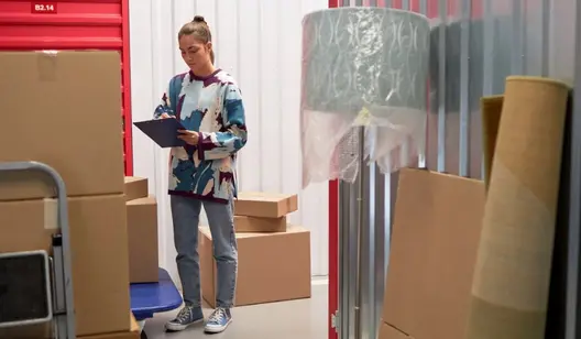 Frau schreibt auf Klemmbrett in Lagerraum