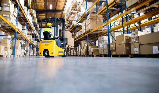 Gelber Gabelstapler transportiert Kisten in Halle