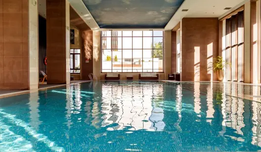Sonne strahlt durch Fenster auf Schwimmbecken in Hallenbad