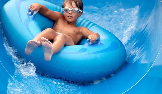 Kind rutscht auf Reifen in Wasserrutsche