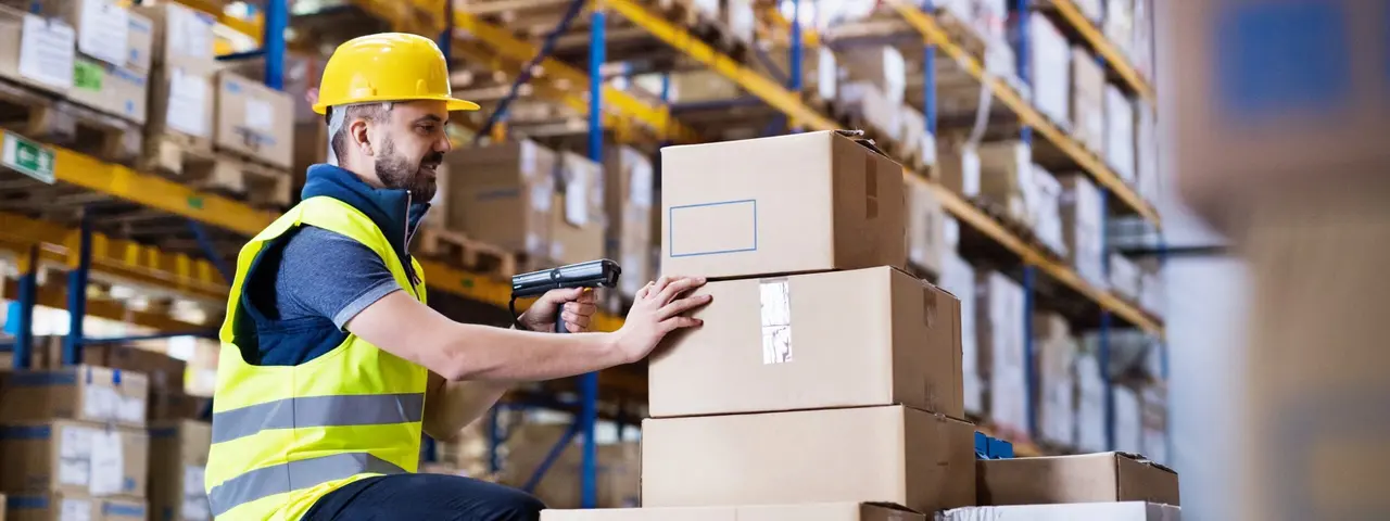 Arbeiter scannt Kisten in Lagerhalle